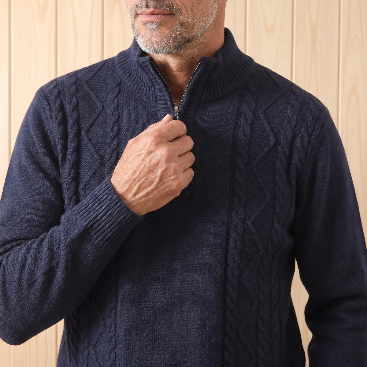 Man zipping up the CABLE PANEL SWEATER in navy blue