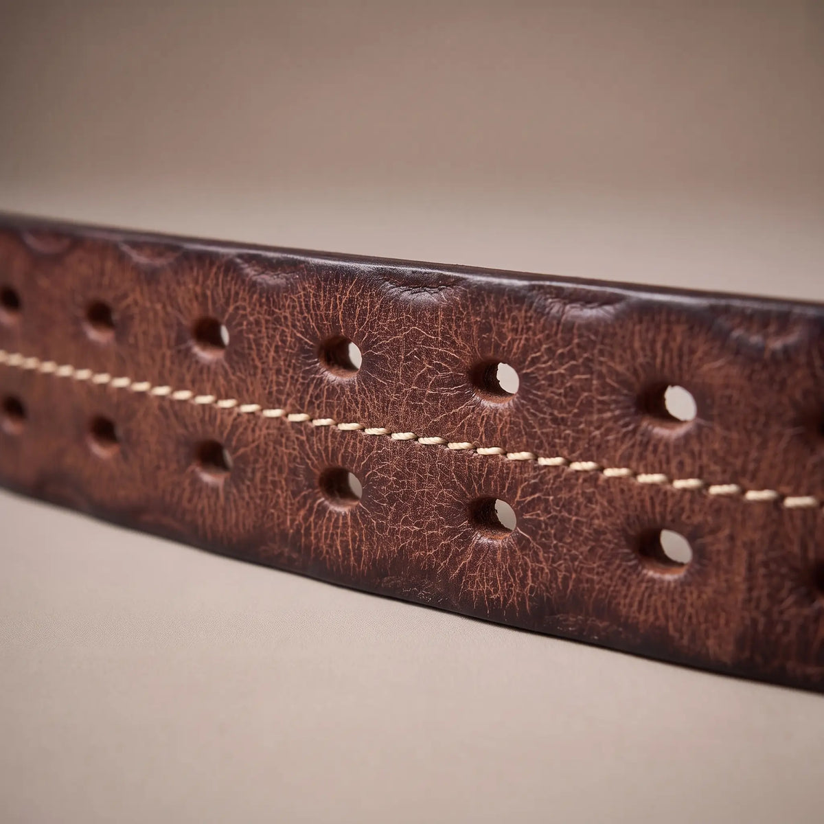 Close-up of the distressed brown cowhide, center stitch and two rows of holes