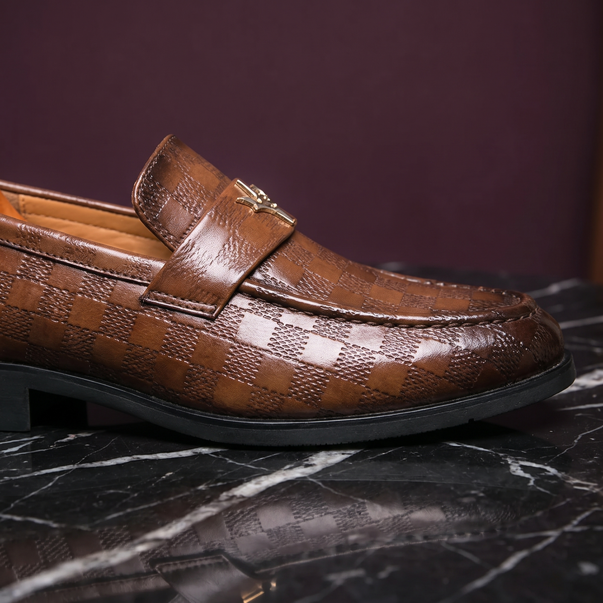 Close-up of the loafer strap, gold ornament and embossed check leather