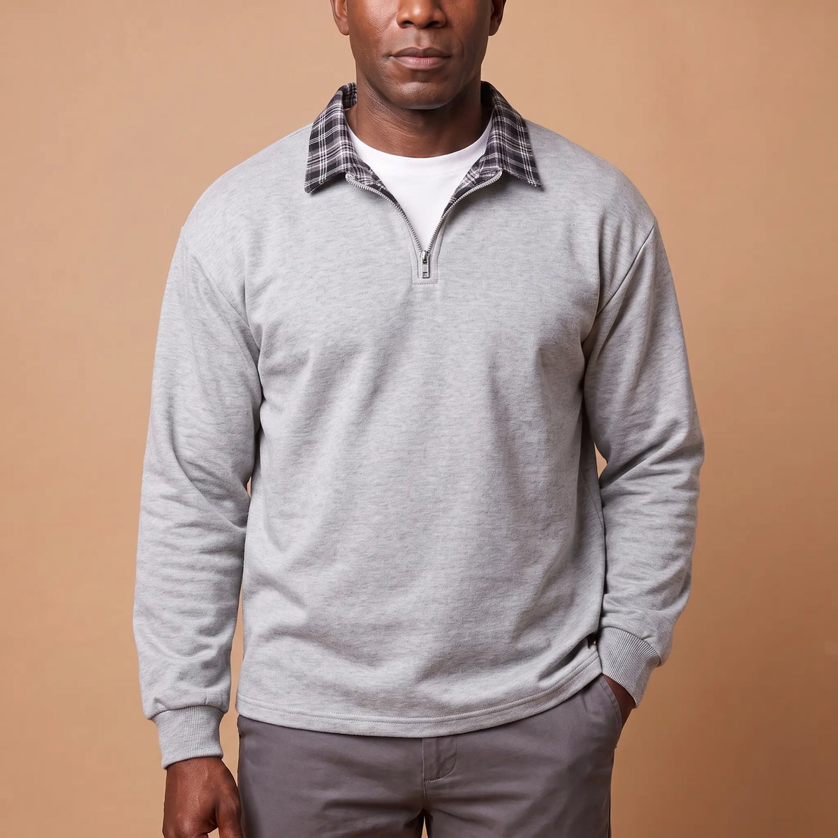 Man wearing light grey half-zip sweatshirt with check shirt collar and grey chinos