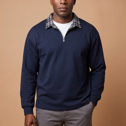 Man wearing navy blue half-zip sweatshirt with check shirt collar and grey chinos