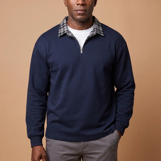 Man wearing navy blue half-zip sweatshirt with check shirt collar and grey chinos