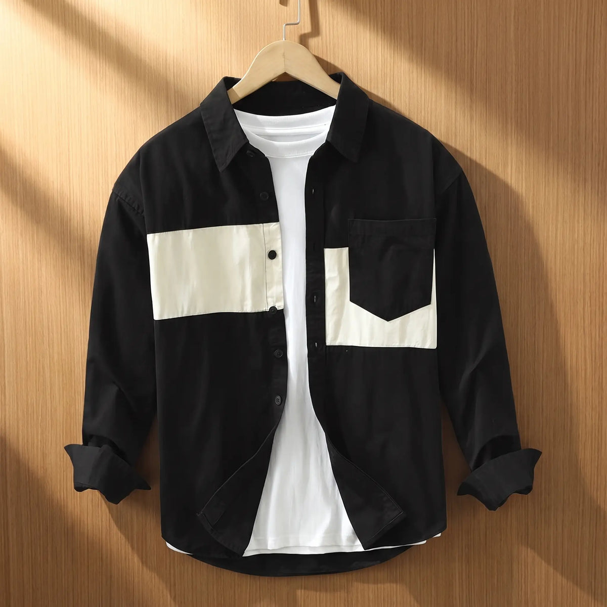Black chest band shirt for men with cream patchwork panels on a wooden hanger