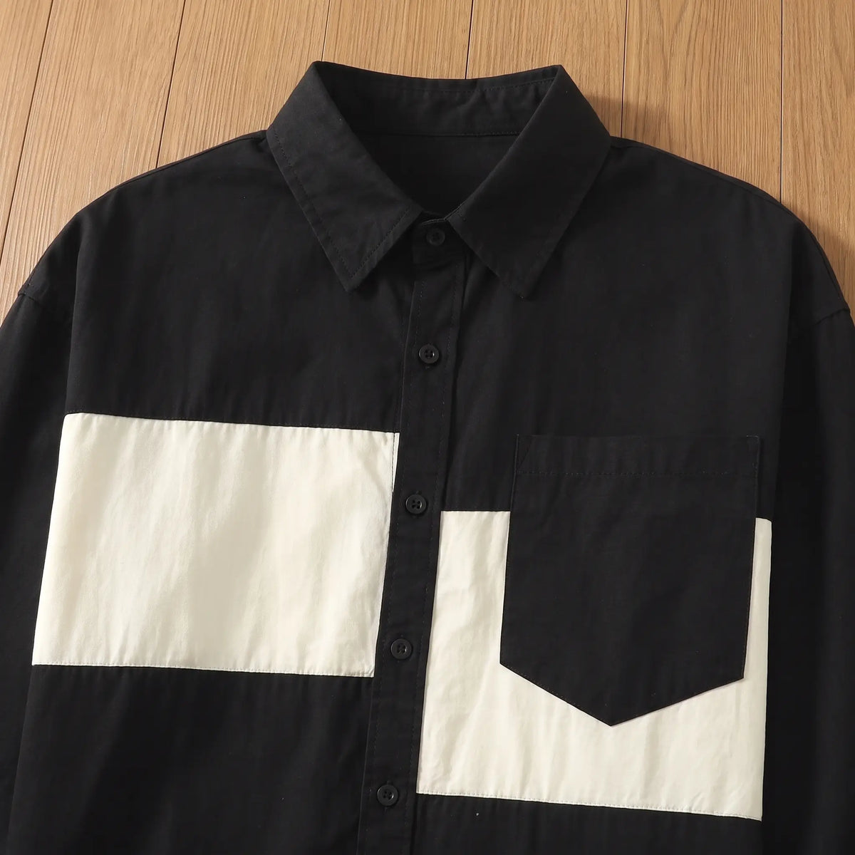Flat lay of the two-tone chest band and pocket on a black cotton shirt for men