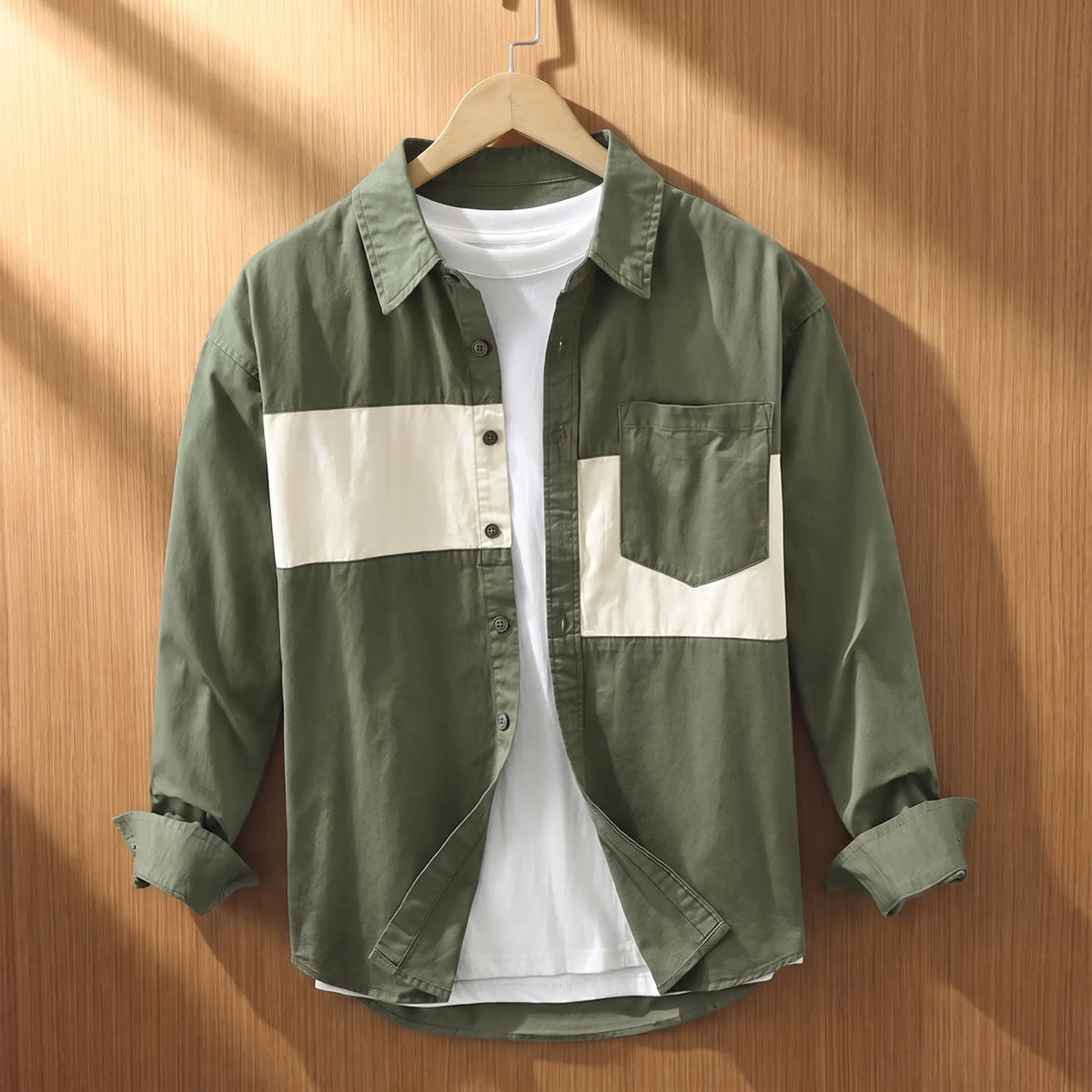 Green chest band shirt for men with cream patchwork panels on a wooden hanger