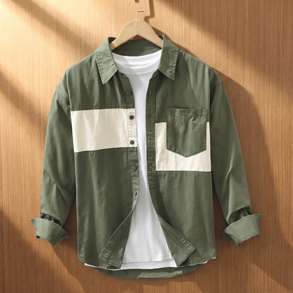 Green chest band shirt for men with cream patchwork panels on a wooden hanger