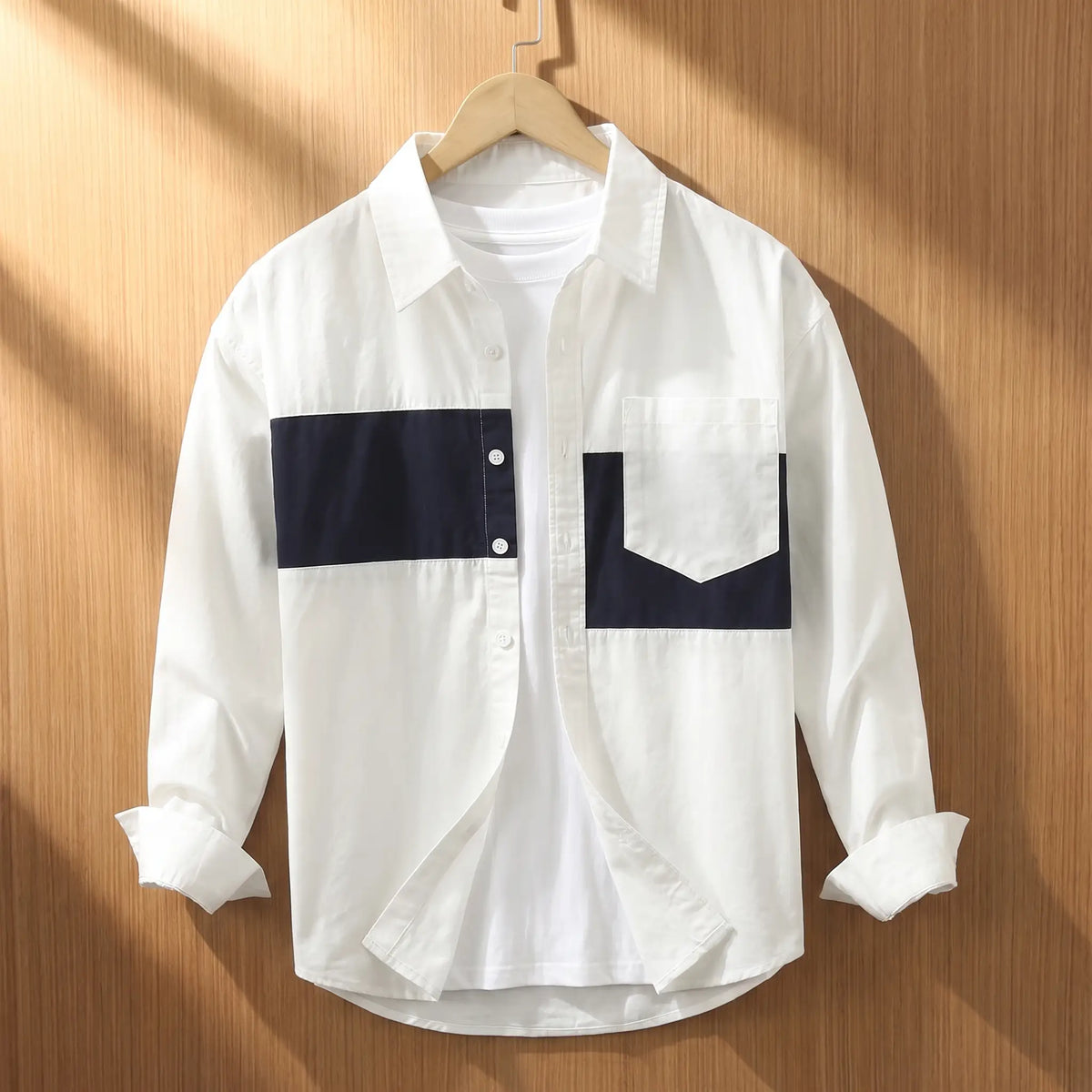 White chest band shirt for men with navy blue patchwork panels on a wooden hanger