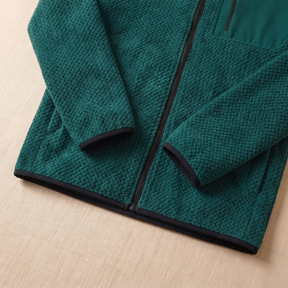Close-up of the bound cuff and hem on the green chevron knit jacket