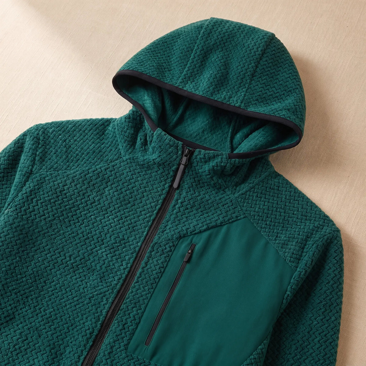Close-up of the hood, front zip and chest pocket on the green knit jacket