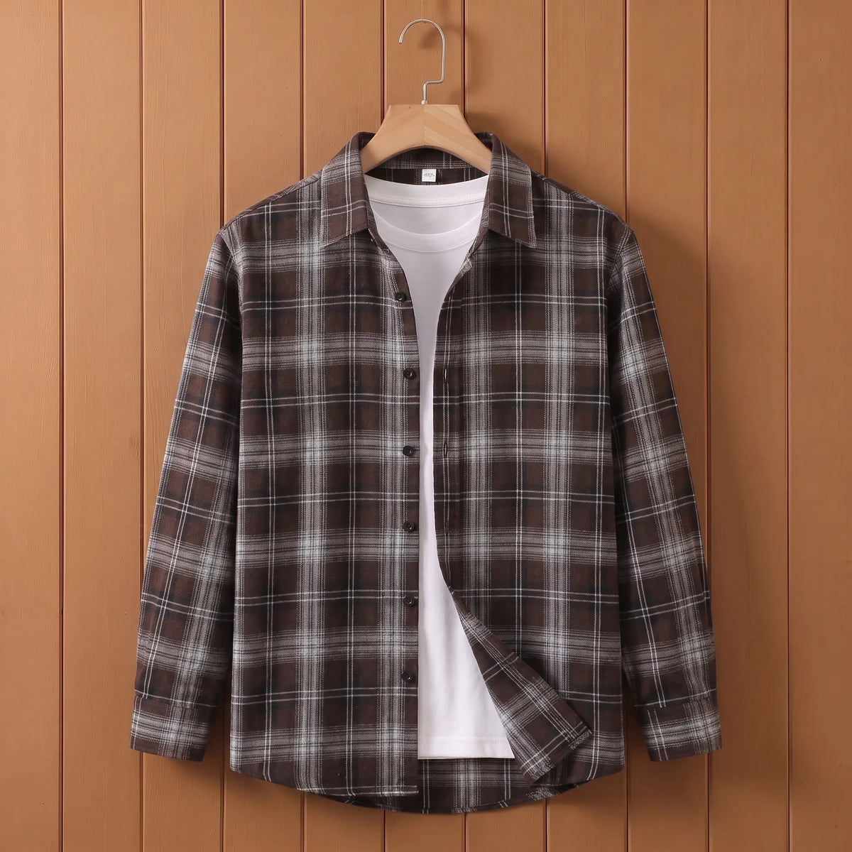 Men's brown plaid long-sleeve button shirt open over a white tee on a wooden hanger
