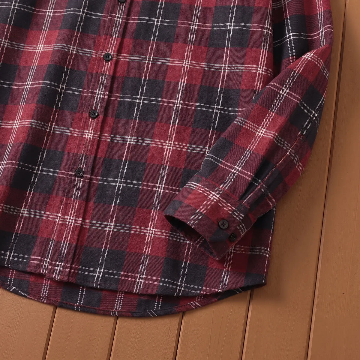 Close-up of red plaid shirt button cuff and curved hem