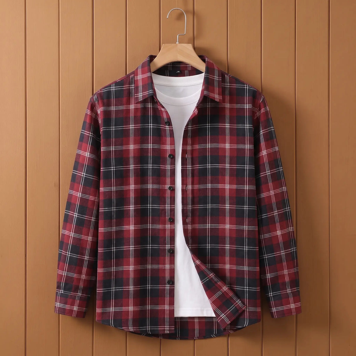 Men's red plaid long-sleeve button shirt open over a white tee on a wooden hanger