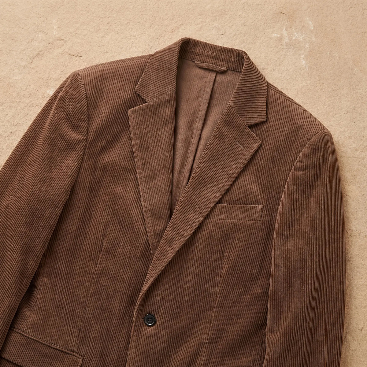 Close-up of brown corduroy blazer notch lapels and button closure