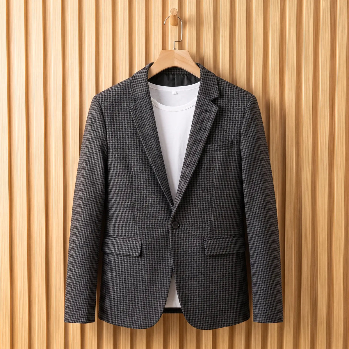 Men's dark grey houndstooth single-button blazer over a white tee on a wooden hanger