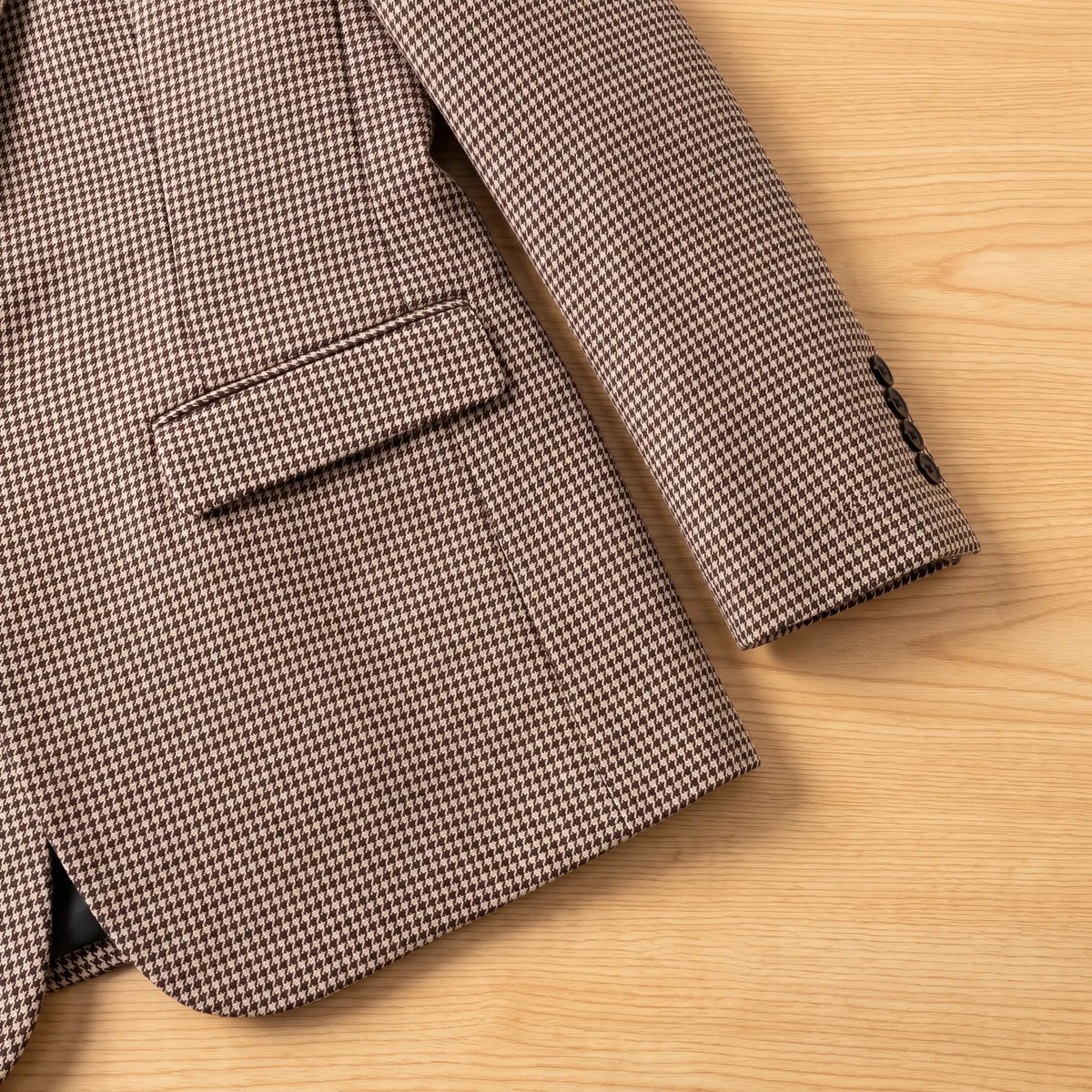 Close-up of brown houndstooth blazer flap pocket and button cuff
