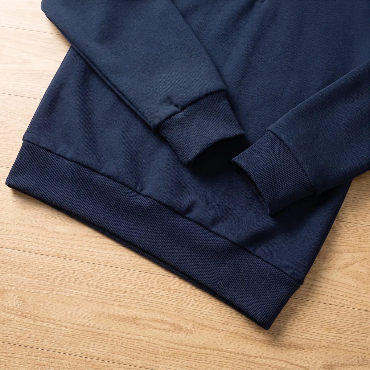 Close up of the ribbed cuff and hem on the navy blue classic zip neck sweatshirt