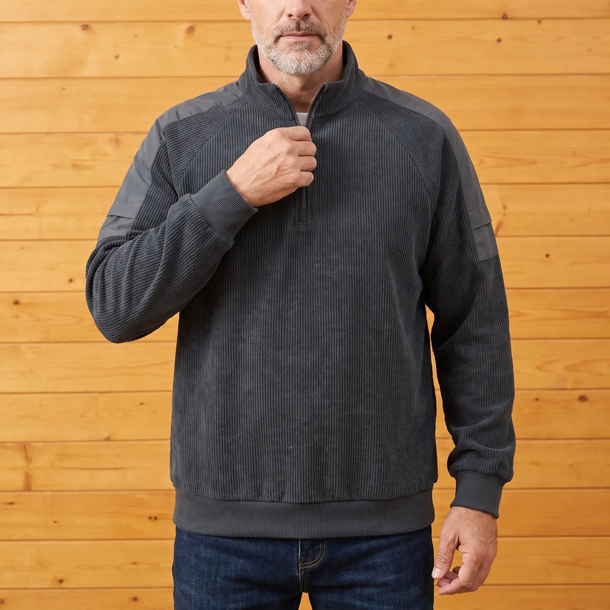 Man zipping up a grey corduroy quarter-zip sweatshirt worn with jeans