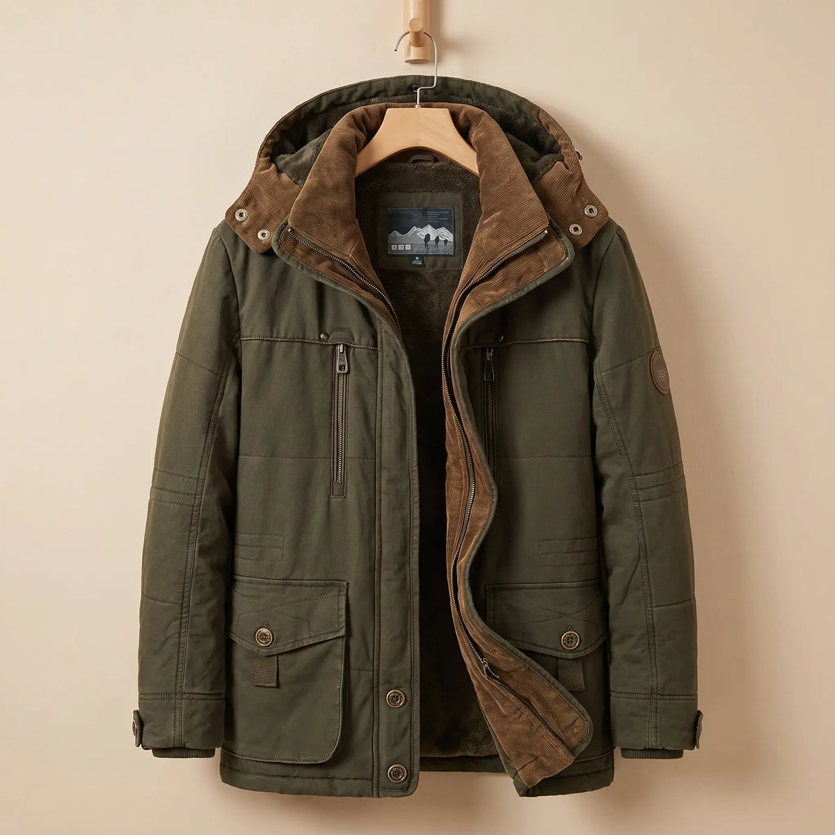 Men's green fleece-lined hooded parka with corduroy collar, zip chest pocket and snap flap pockets on a wooden hanger