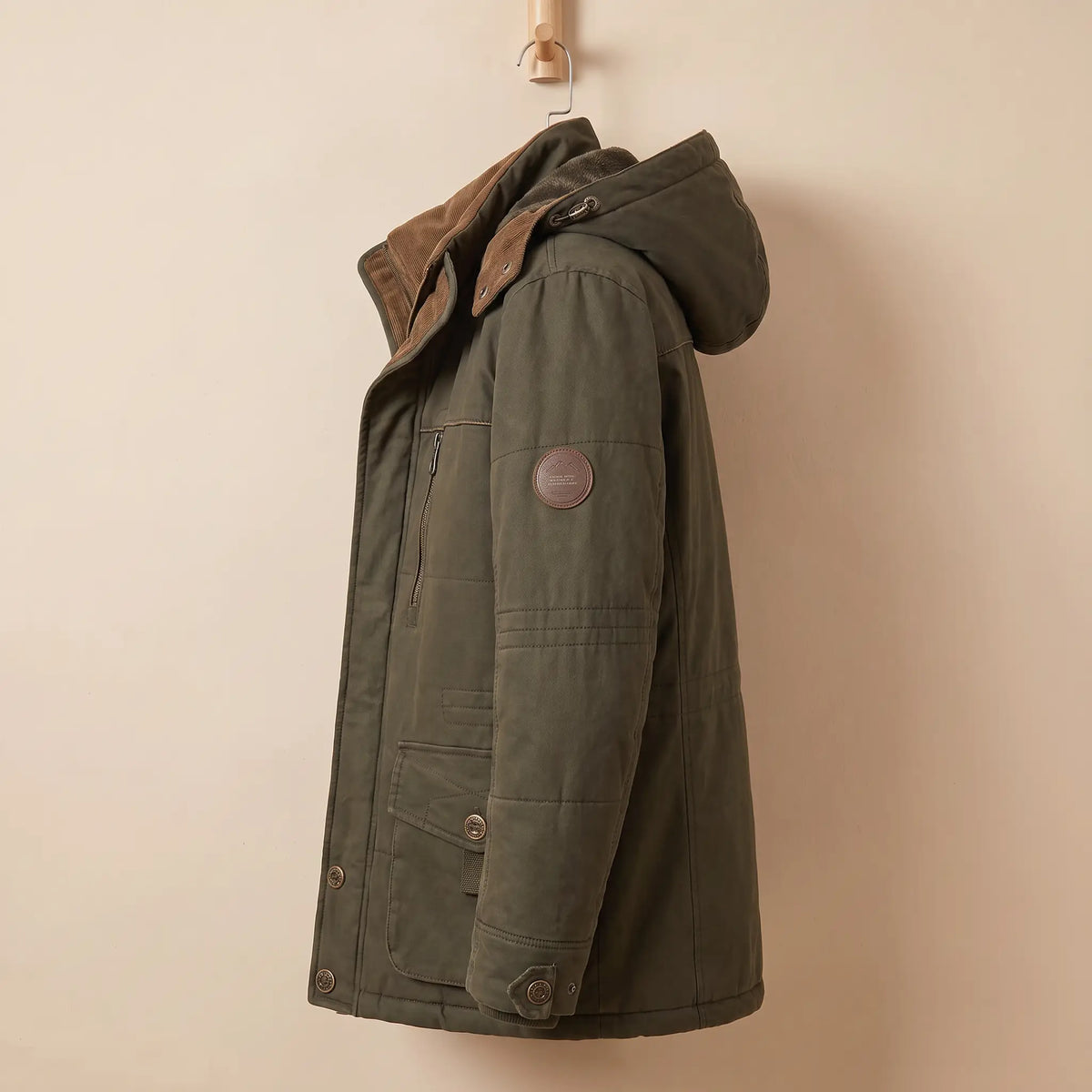 Side view of green fleece-lined parka zipped with hood up, sleeve patch visible