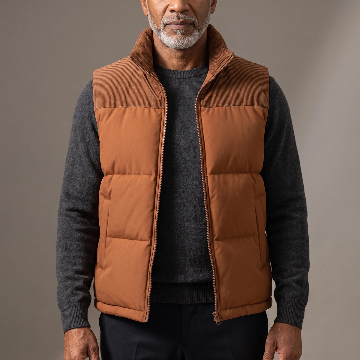 Men's brown quilted puffer vest with ribbed cord collar and shoulder yoke, worn open over a charcoal knit