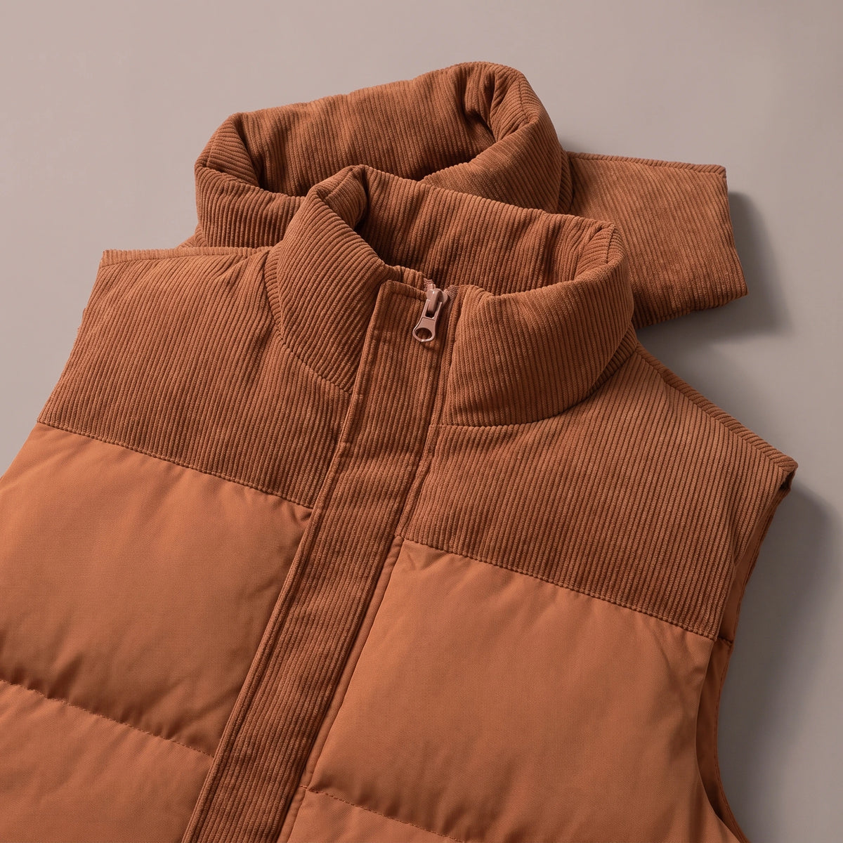 Close-up of the ribbed cord stand collar, shoulder yoke and zip pull on the brown puffer vest