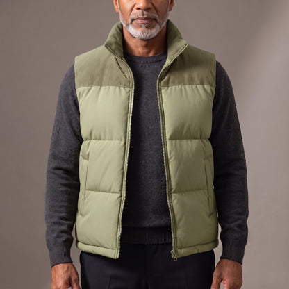 Men's green quilted puffer vest with ribbed cord collar and shoulder yoke, worn open over a charcoal knit