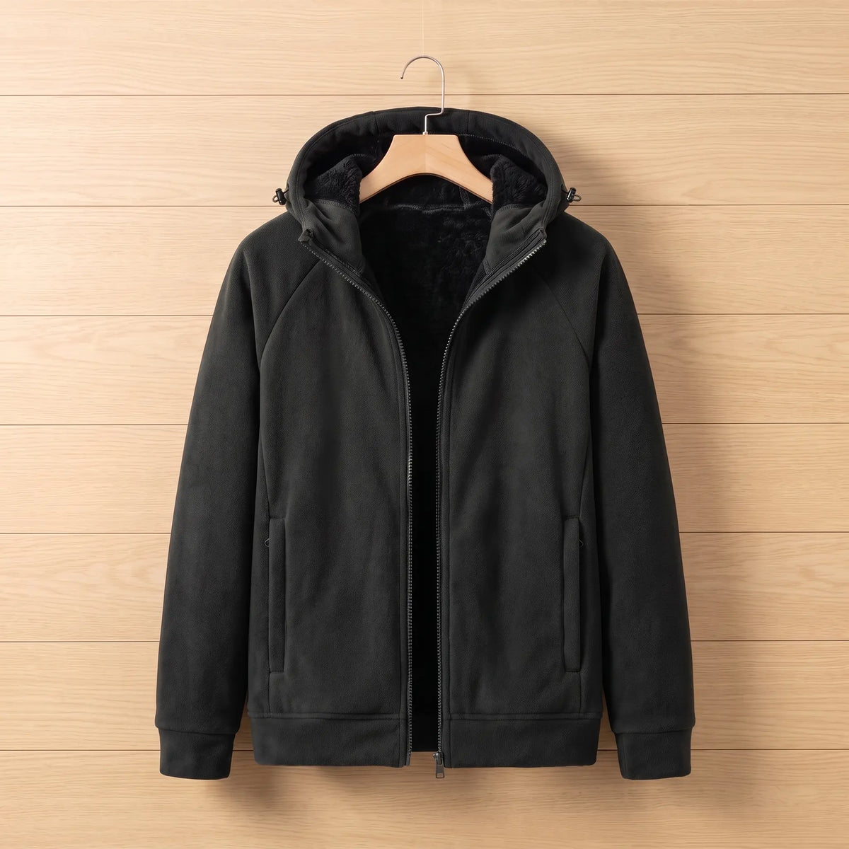 Men's black full-zip fleece jacket with black plush-lined hood, zip pockets and ribbed cuffs on a wooden hanger