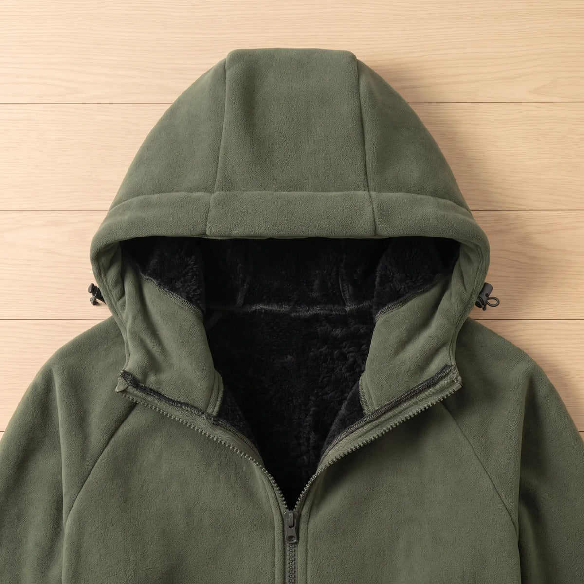 Close-up of green fleece jacket hood showing black plush lining and drawcord toggles