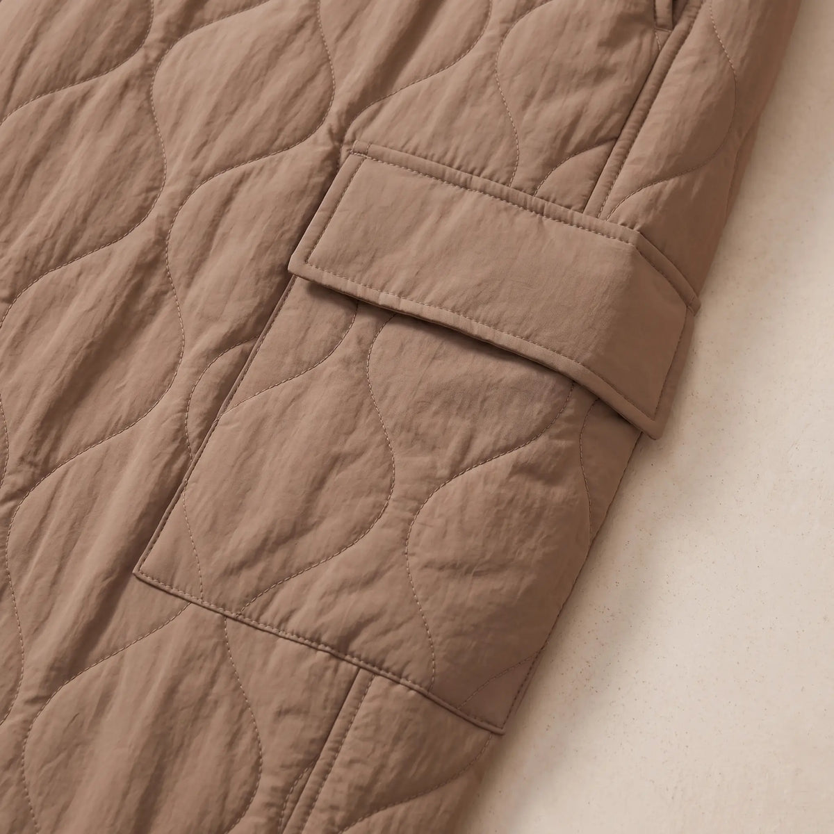 Close up of the COSY QUILTED TROUSERS flap cargo pocket and quilting