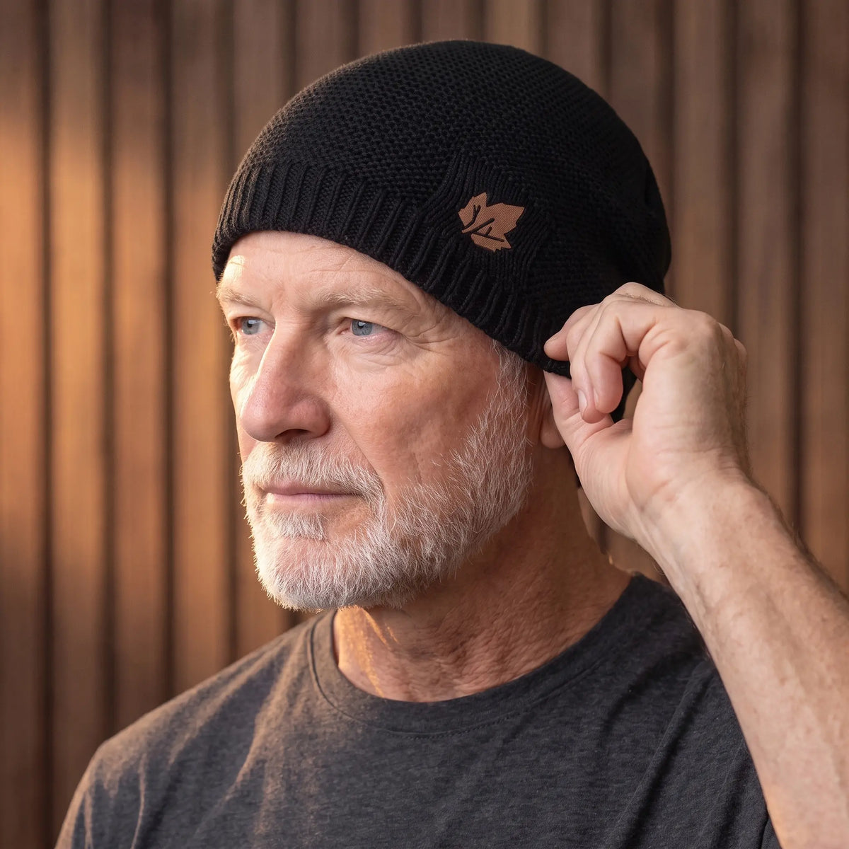 Man pulling the black knit beanie down over his ear