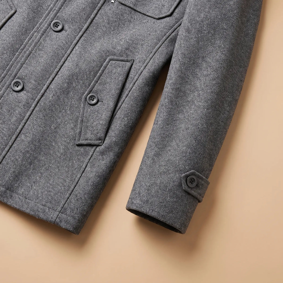Close up of the DOUBLE COLLAR COAT buttoned cuff tab and angled welt pocket at the hem