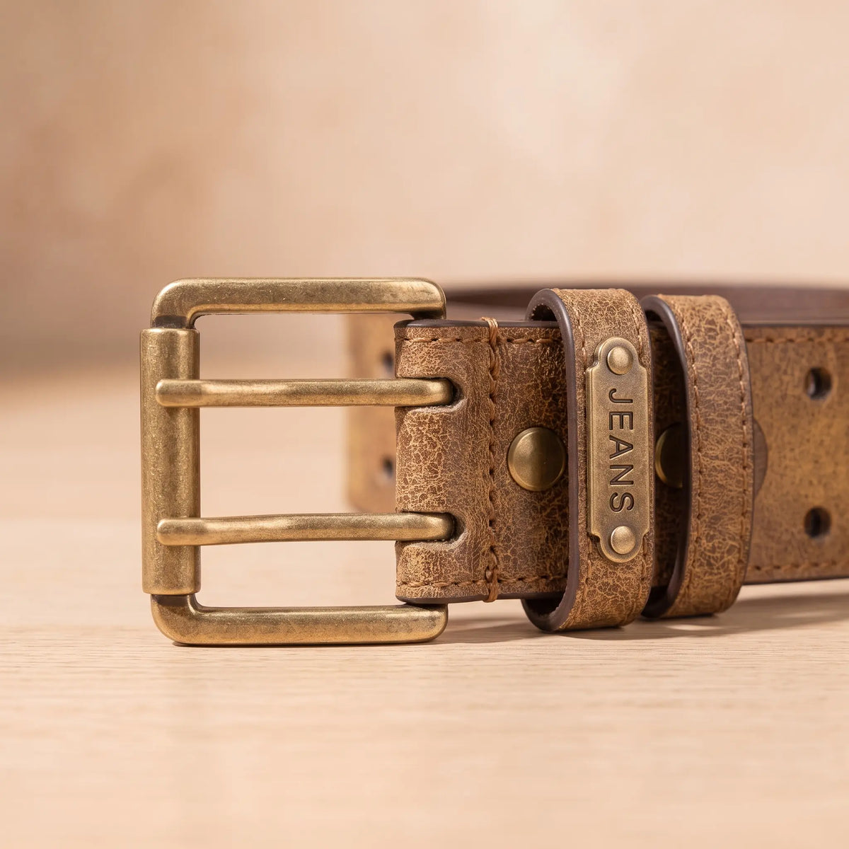 Close up of the DOUBLE PIN BELT antique brass double prong buckle, keeper loops and stitched strap edge