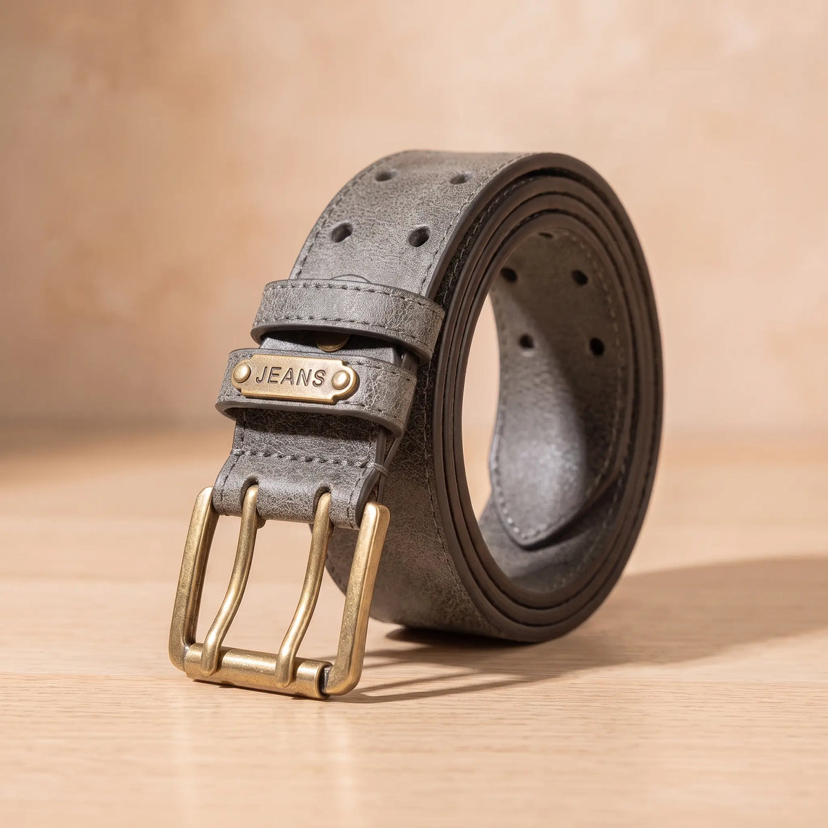 DOUBLE PIN BELT in grey, aged finish belt with antique brass double prong buckle, coiled on light oak