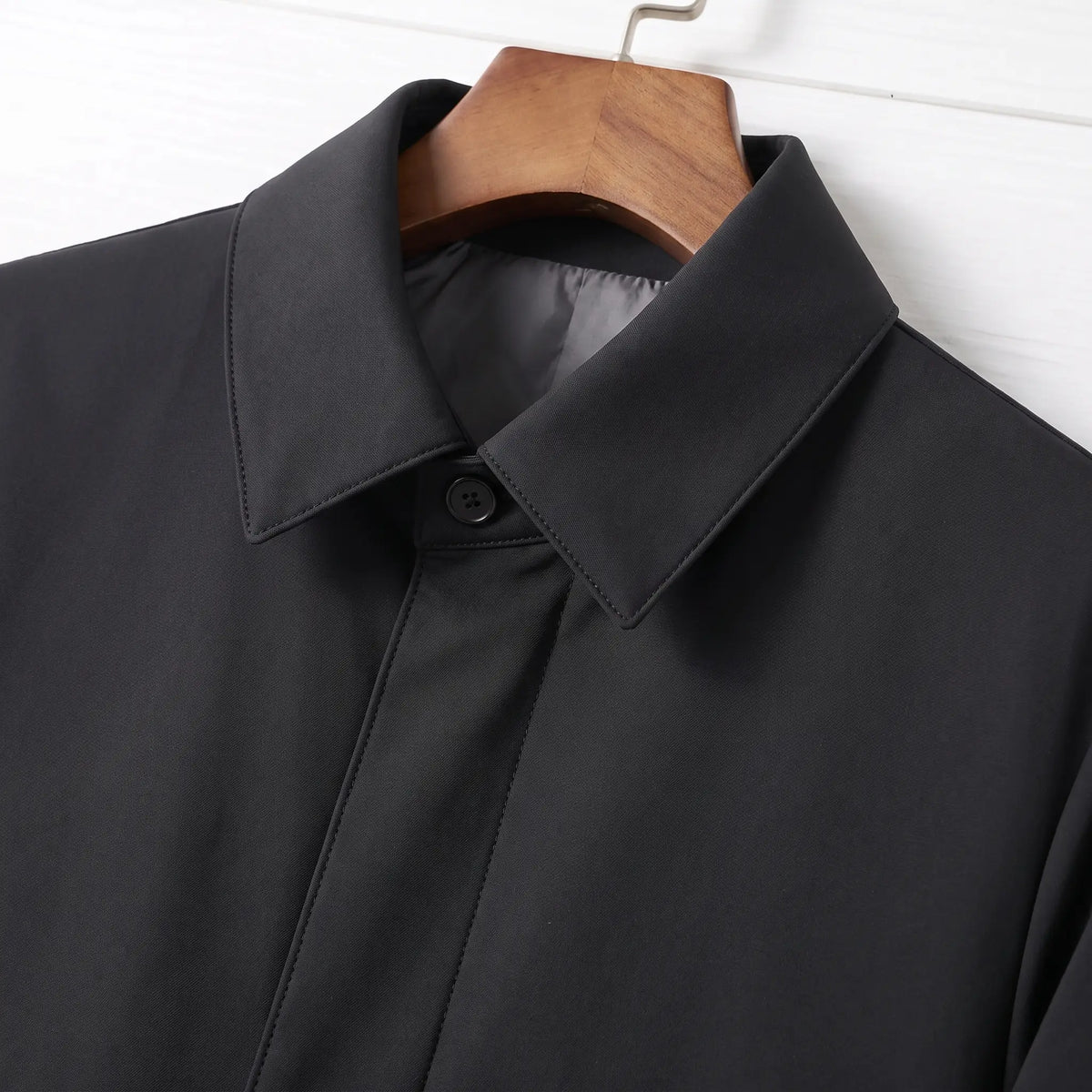 Close-up of the pointed collar and hidden button front on a black down lined coat for men