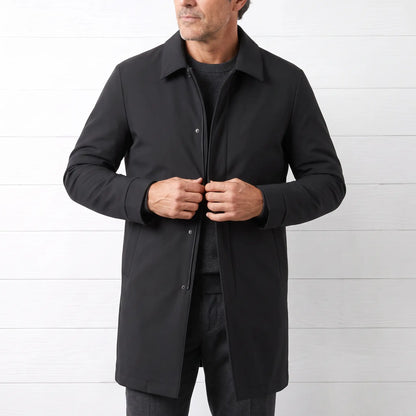 Man buttoning a black down lined coat over a grey knit and charcoal trousers