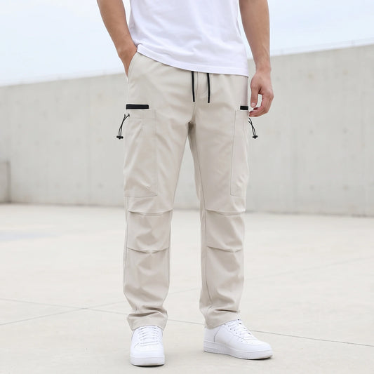 Men's beige drawcord cargo trousers worn with a white tee, relaxed straight leg with thigh pockets and pleated knees