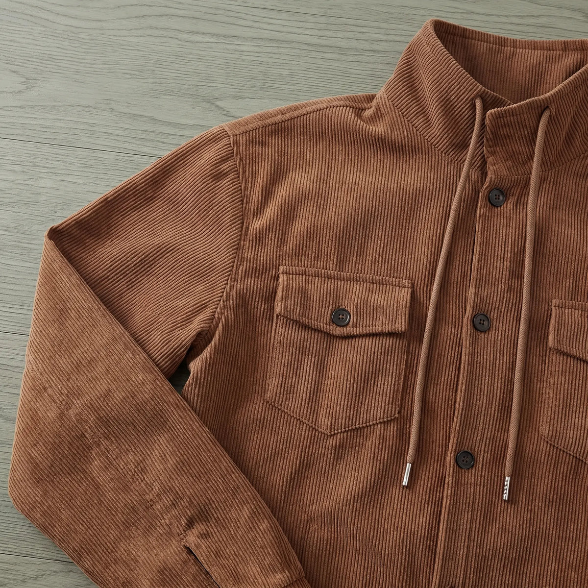 Close up of the drawcord collar and buttoned chest pocket on the brown drawcord collar jacket