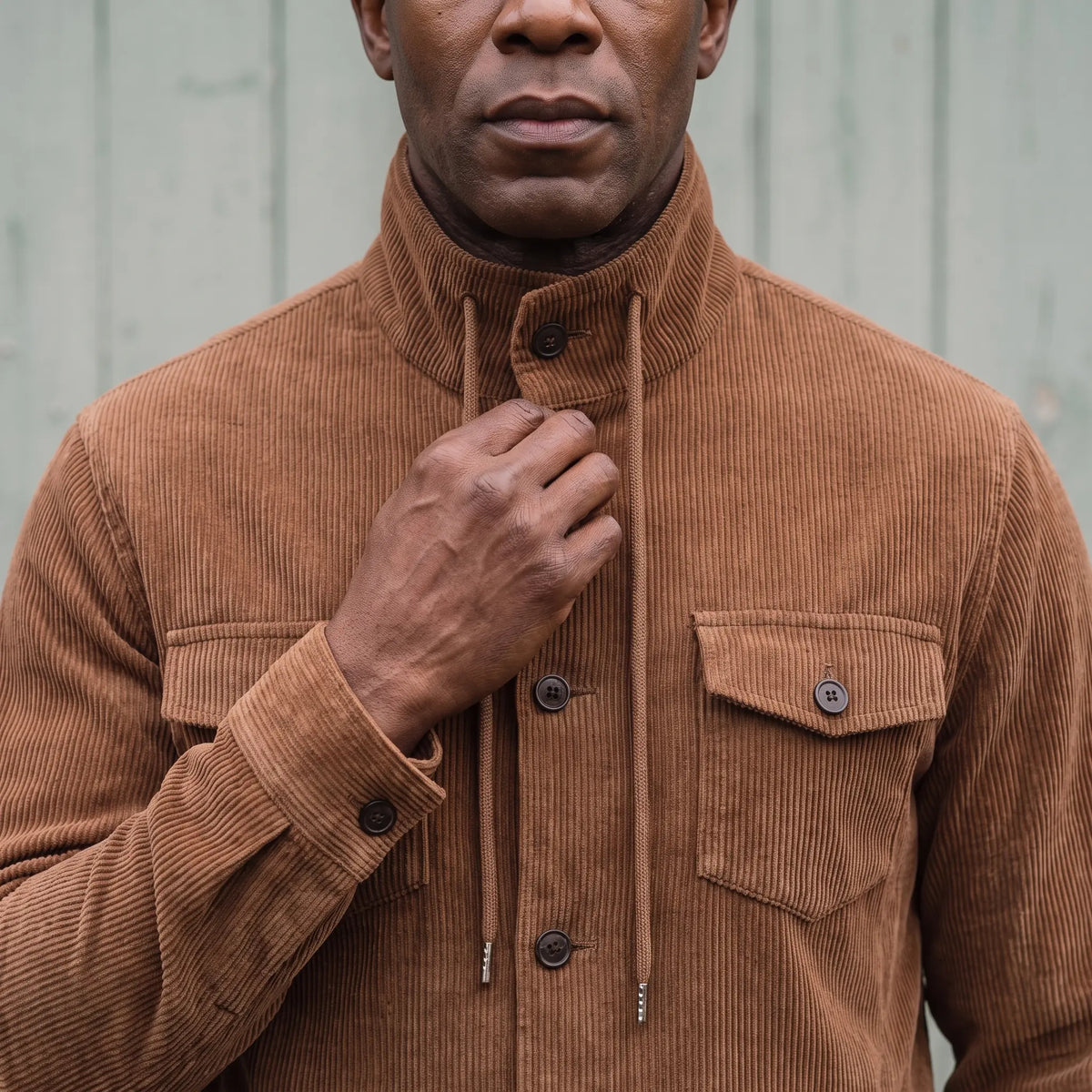 Man fastening the collar button on the brown drawcord collar jacket
