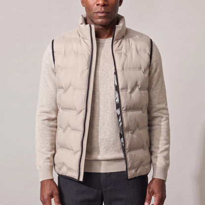 Men's beige duck down vest with stand-up collar, worn open over an oatmeal sweater