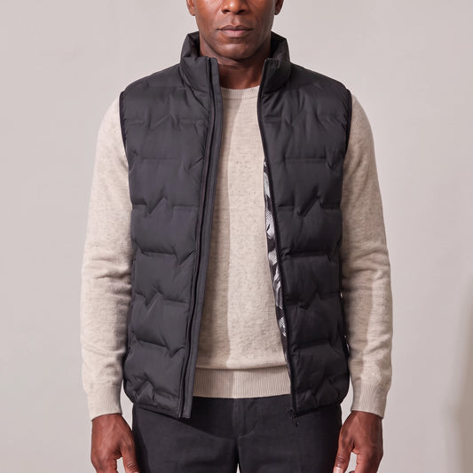 Men's black duck down vest with wave quilting, worn open over an oatmeal sweater
