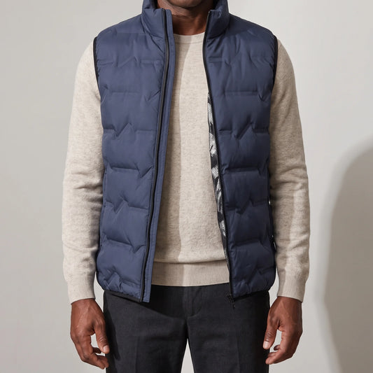 Men's navy duck down vest with stand-up collar, worn open over an oatmeal sweater