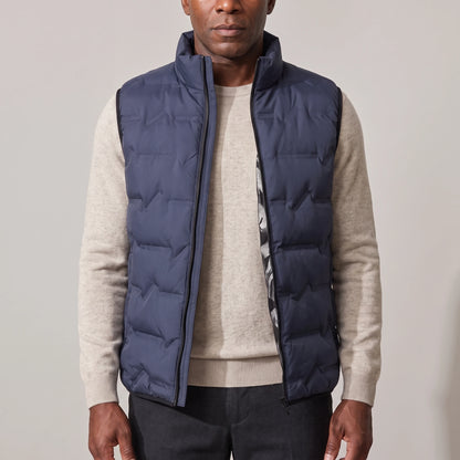 Men's navy blue duck down vest with stand-up collar, worn open over an oatmeal sweater