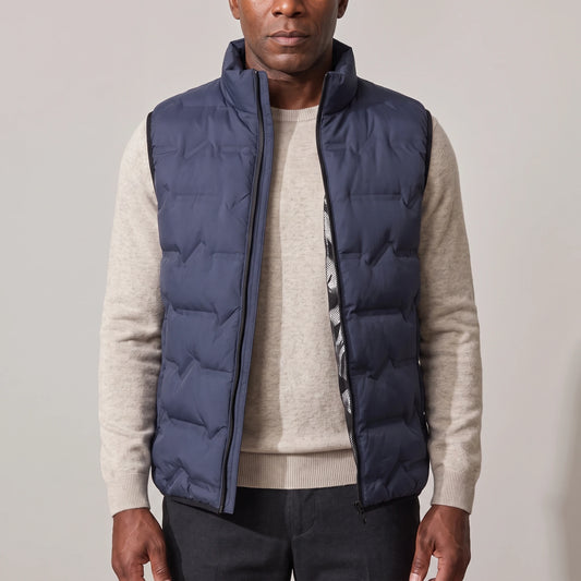 Men's navy blue duck down vest with stand-up collar, worn open over an oatmeal sweater