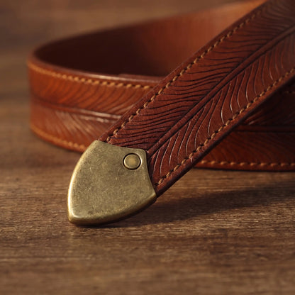 Close-up of the feather embossing and metal tip on the tan cowhide belt strap