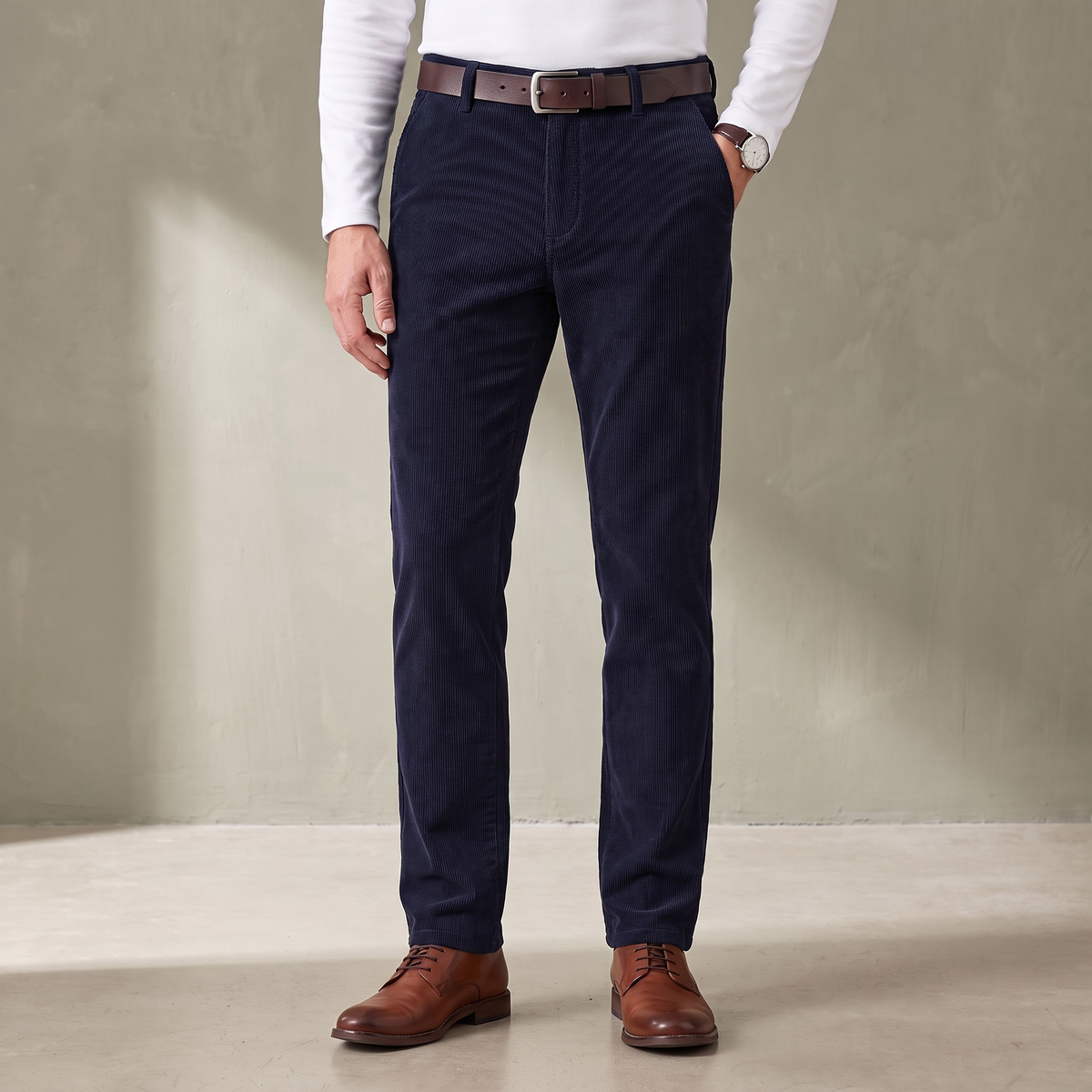 Navy fine wale corduroy trousers worn with a brown leather belt and derby shoes