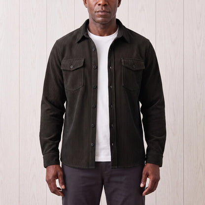 Man wearing the Fine Cord Overshirt in black, a corduroy shirt jacket open over a white tee