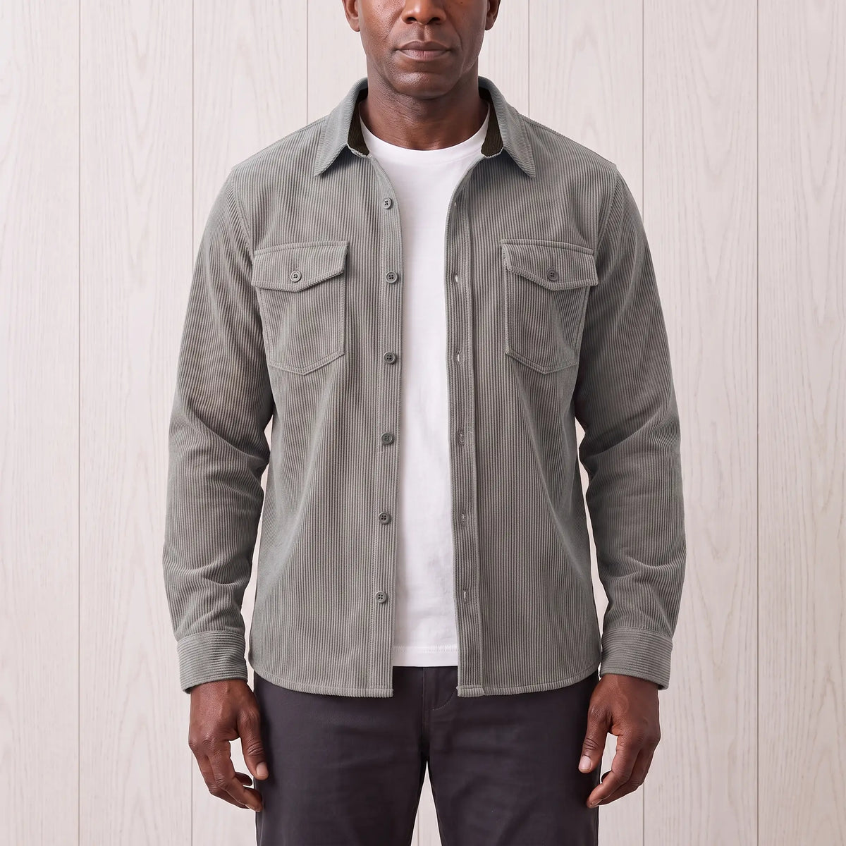 Man wearing the Fine Cord Overshirt in grey, a corduroy shirt jacket open over a white tee