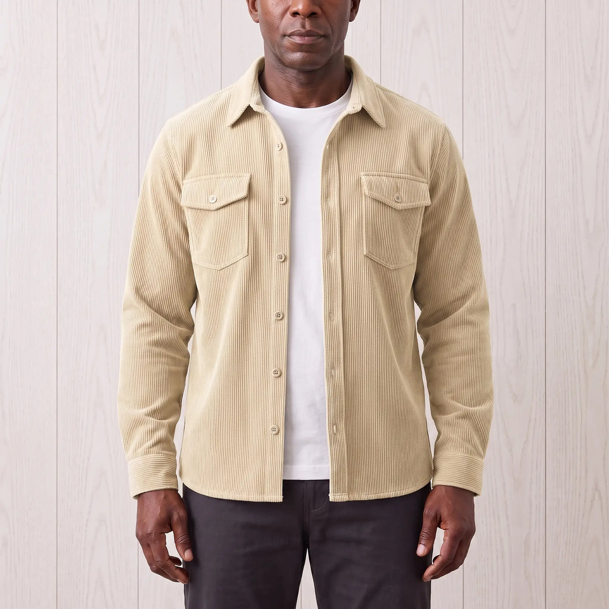 Man wearing the Fine Cord Overshirt in white, a cream corduroy shirt jacket open over a white tee