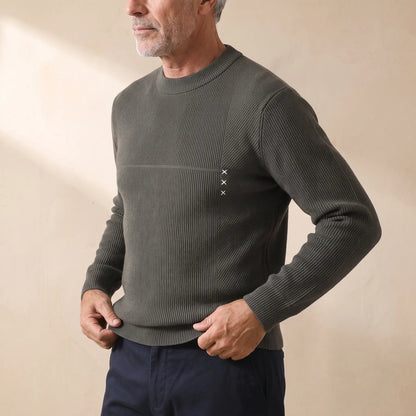 Man wearing the green fine rib sweater, pulling down the hem