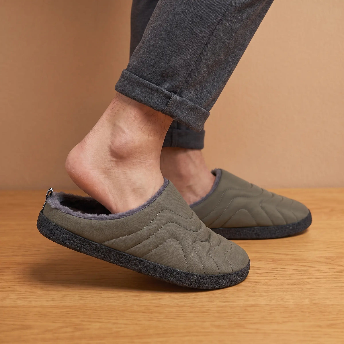Man stepping into green quilted slippers wearing grey lounge pants